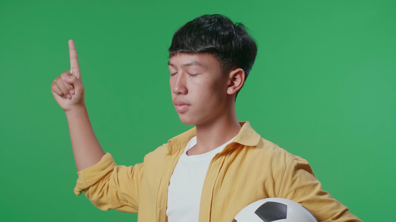 십대 는 축구 공 을 들고 가리키고 있다