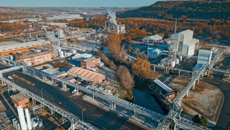 Aerial-footage-moving-towards-a-large-industrial-chemical-plant,-showing-pipelines,-metal-structures,-cooling-towers-and-chemical-storage