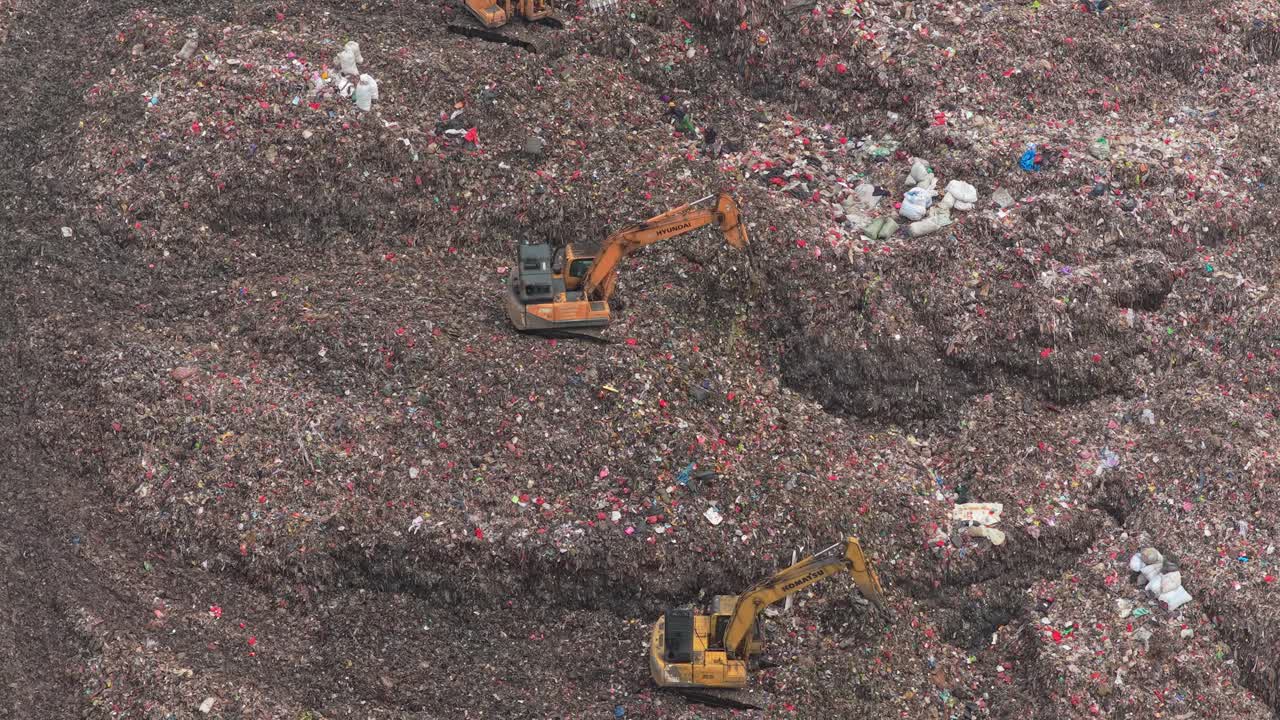 Escavatori al lavoro in una massiccia discarica che spostano i rifiuti