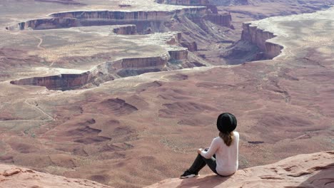 Toma-En-Cámara-Lenta-De-Una-Turista-Sentada-En-Una-Roca-Disfrutando-De-La-Isla-En-El-Cielo-En-El-Parque-Nacional-Canyonlands-En-Utah,-Estados-Unidos