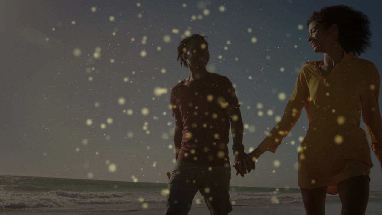 Camera starting at feet and showing couple walking handholding on shore romance sparkles overlaying