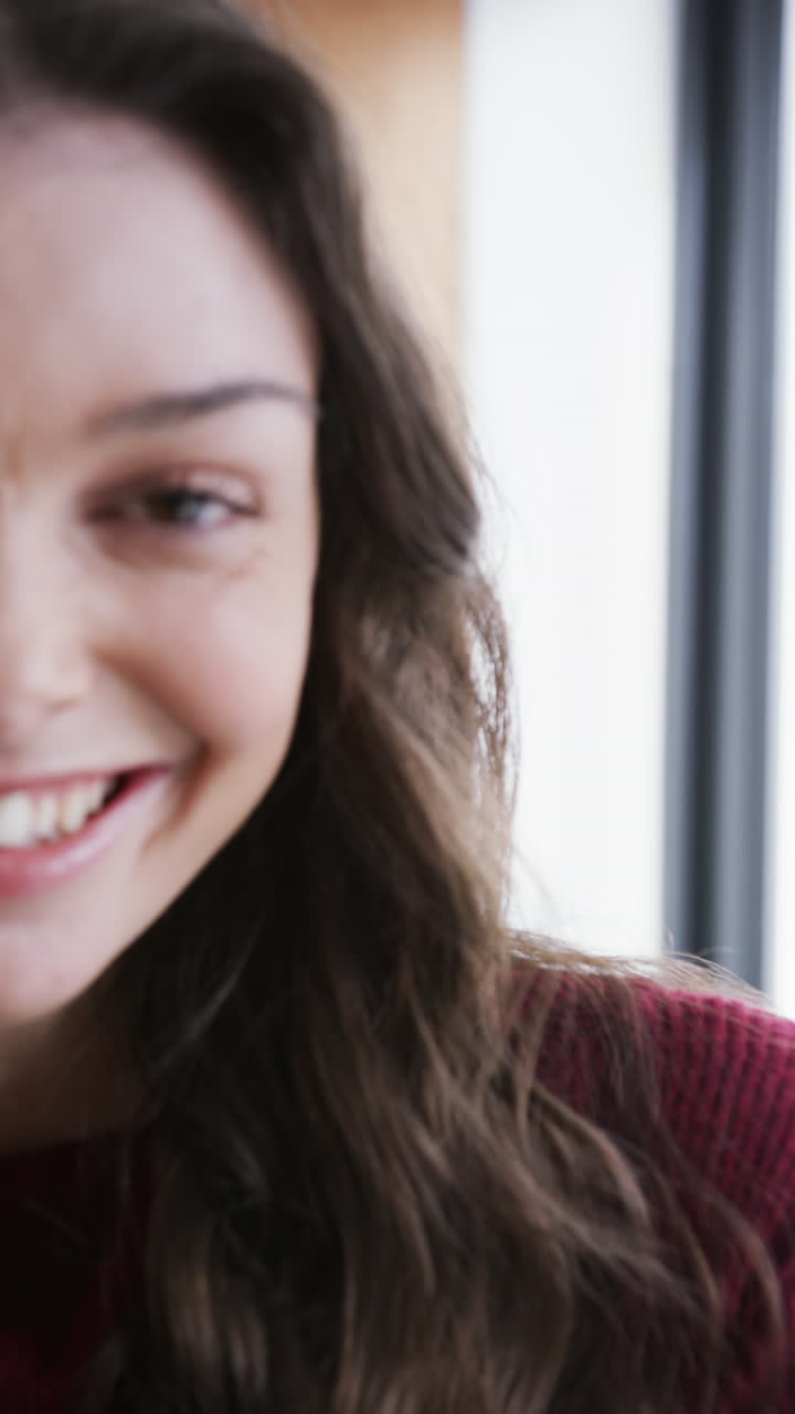 Half face of happy caucasian woman standing by window and smiling, slow motion