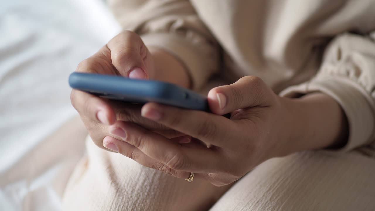 mujer usando un teléfono inteligente mientras está sentada en una cama