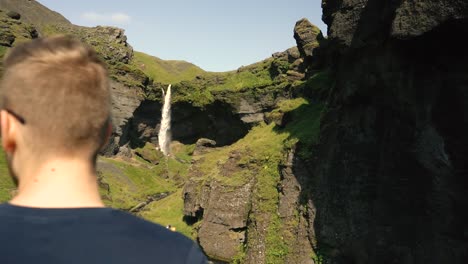 hombre tocando la guitarra frente a una hermosa cascada en islandia-5