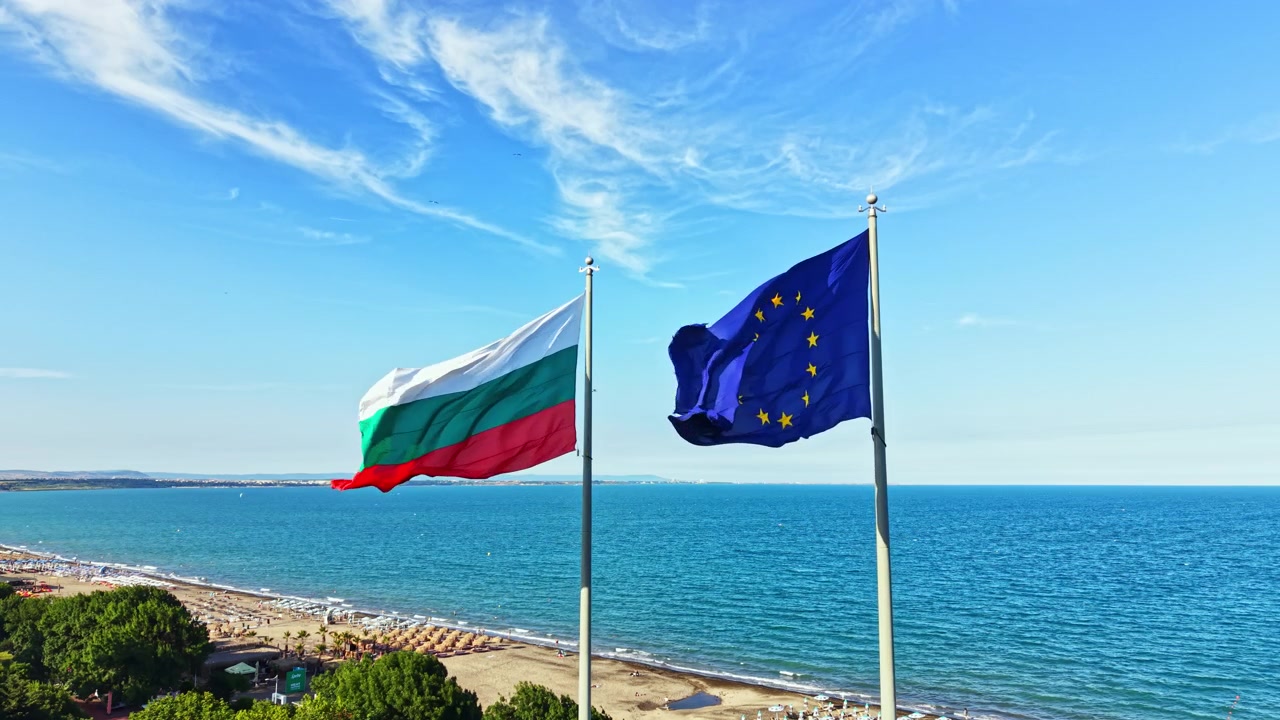 Due bandiere sventolano su una scena di spiaggia in Bulgaria con il mare sullo sfondo e cieli azzurri e limpidi sopra durante una giornata di sole