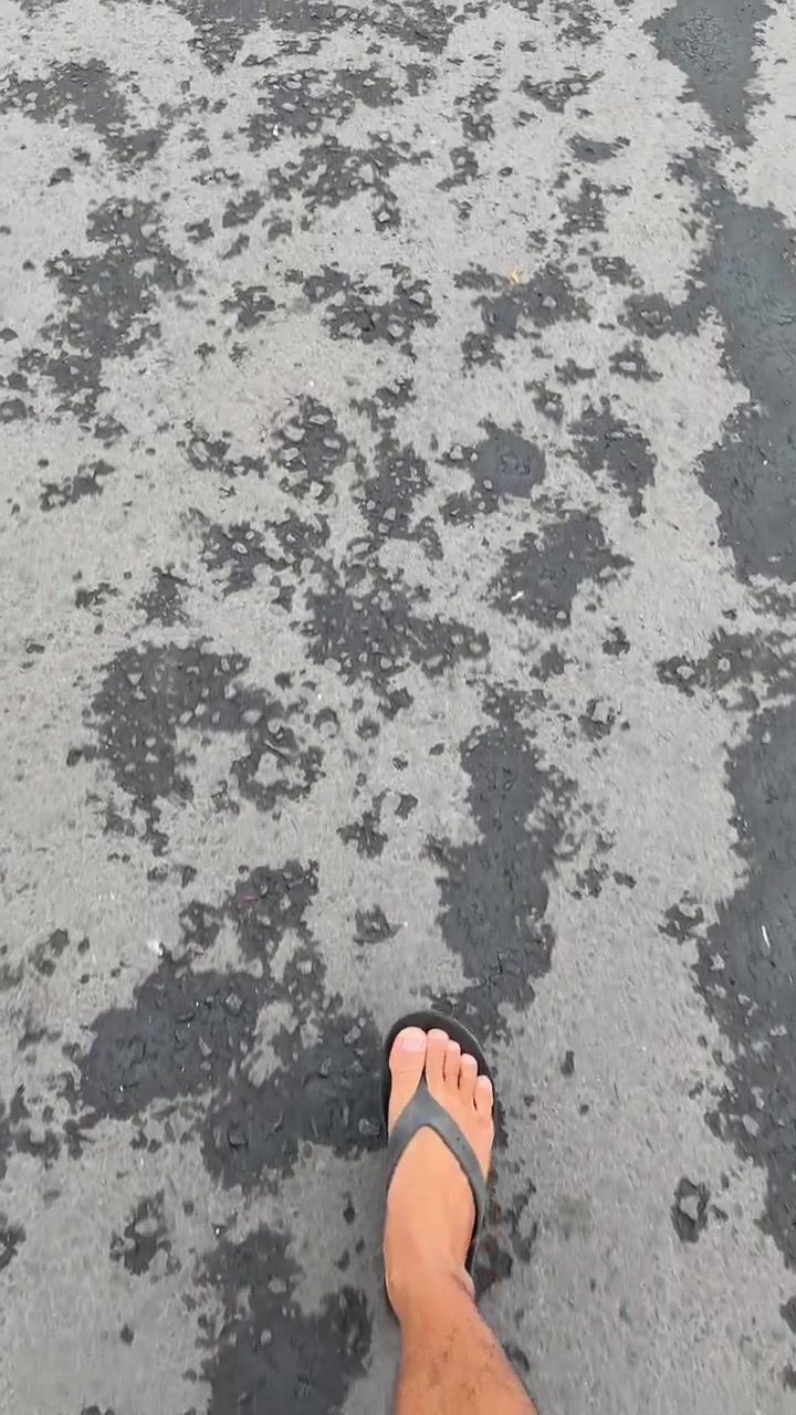 Islak asfalt yolda yalın ayak yürüyen kişi