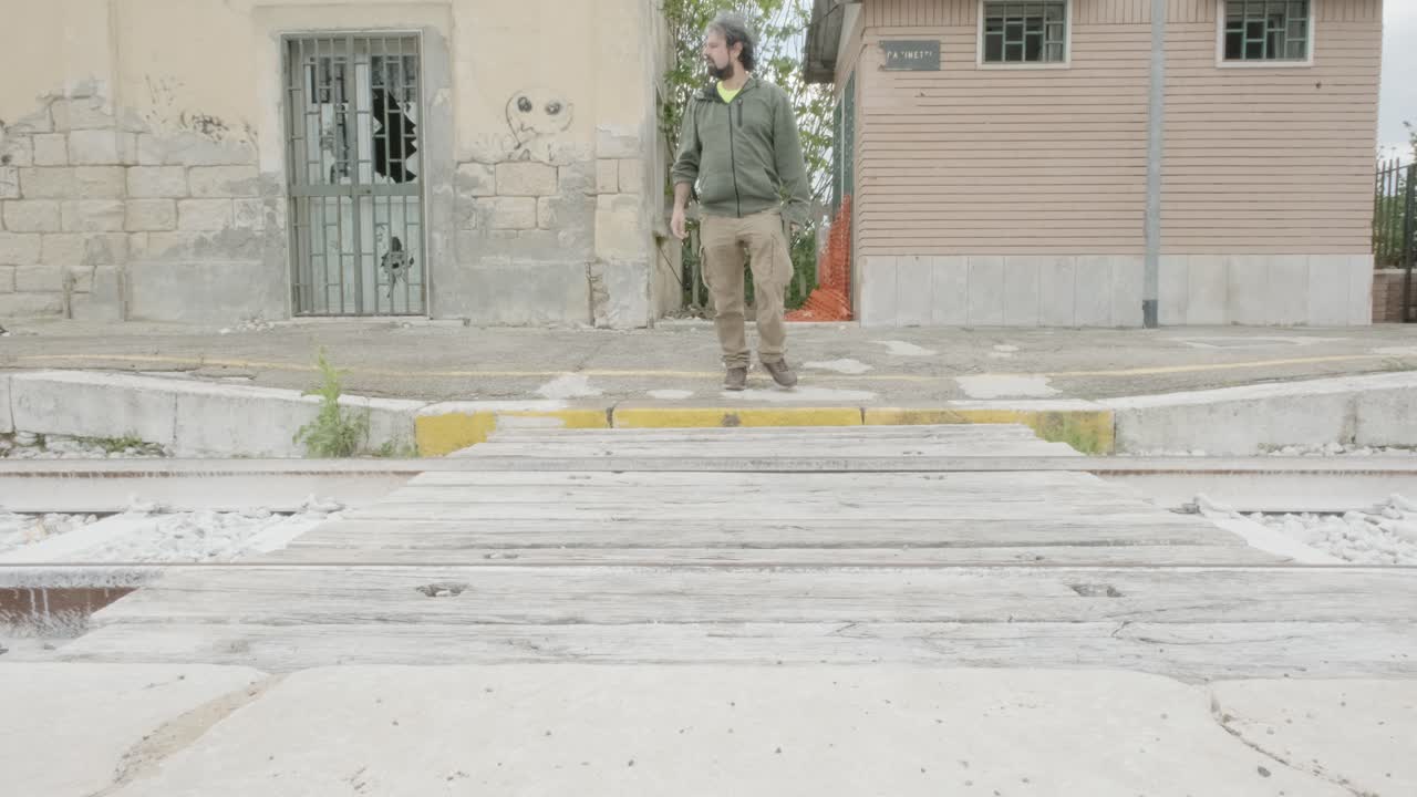 한 쪽에서 다른 쪽으로 그리고 뒤로 은 철도를 가로지르는 사람, 조심스럽게, 들어오는 열차를 둘러보고