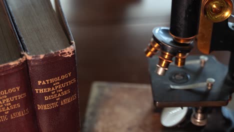 viejos libros de referencia para veterinarios y un microscopio antiguo en el consultorio de un médico animal