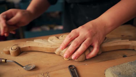 craftswoman polishing wooden detail in workshop