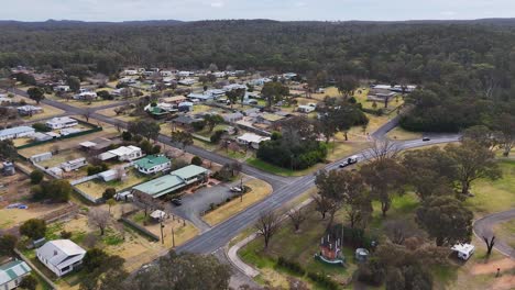 drone footage glides above a quiet rural neighborhood, highlighting local streets, houses, and open green spaces under overcast natural daylight