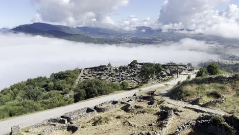 una amplia vista de las ruinas celtas en santa tecla, galicia, con un telón de fondo de montaña brumoso y una niebla baja y pesada