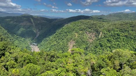 alta vista aérea sobre escarpes rocosos, con vistas a un valle profundo para revelar la impresionante vista de la densa selva tropical envuelta en montañas del norte de queensland