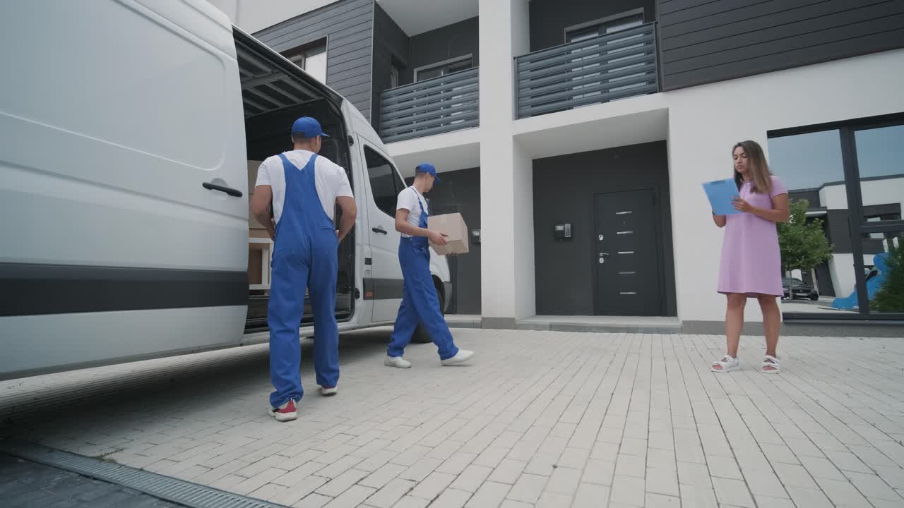 dos jóvenes trabajadores de una empresa de mudanzas descargan cajas del minibús en la casa del cliente