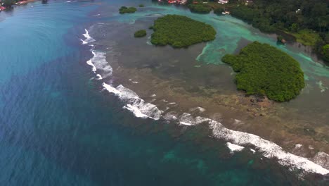 Aerial-view-over-Panama-tropical-island-turquoise-bay-pull-back-revealing-jungle-mountains