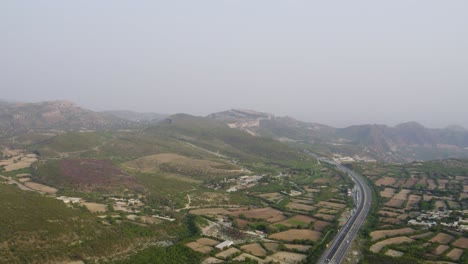 aerial shot of kallar kahar valley, highway winding through patchwork fields and hills. punjab, pakistan