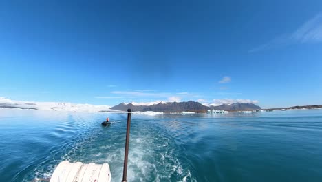 the breathtaking sight of snow-covered mountains in iceland at jökulsárlón glacier lagoon, perfectly captured with a serene boat gracefully gliding through the scene