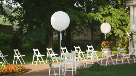 boda establecida en el jardín, parque. ceremonia de boda al aire libre, celebración. decoración del pasillo de la boda. filas de sillas vacías de madera blanca en el césped antes de la ceremonia de boda