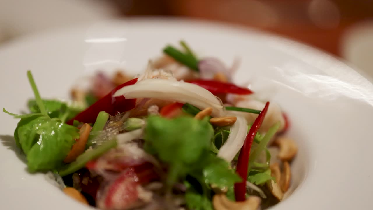una colorida ensalada tailandesa con verduras frescas, chile y fideos, capturada en primer plano con una iluminación suave