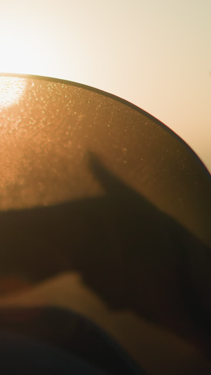 A close-up of a person s hand, adorned with a green bracelet, cleaning the windshield of a motorcycle