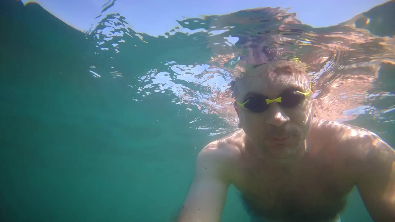 Undervanns filmopptak av en svømmer som snorkler i klart blått sjøvann under sommerferien.