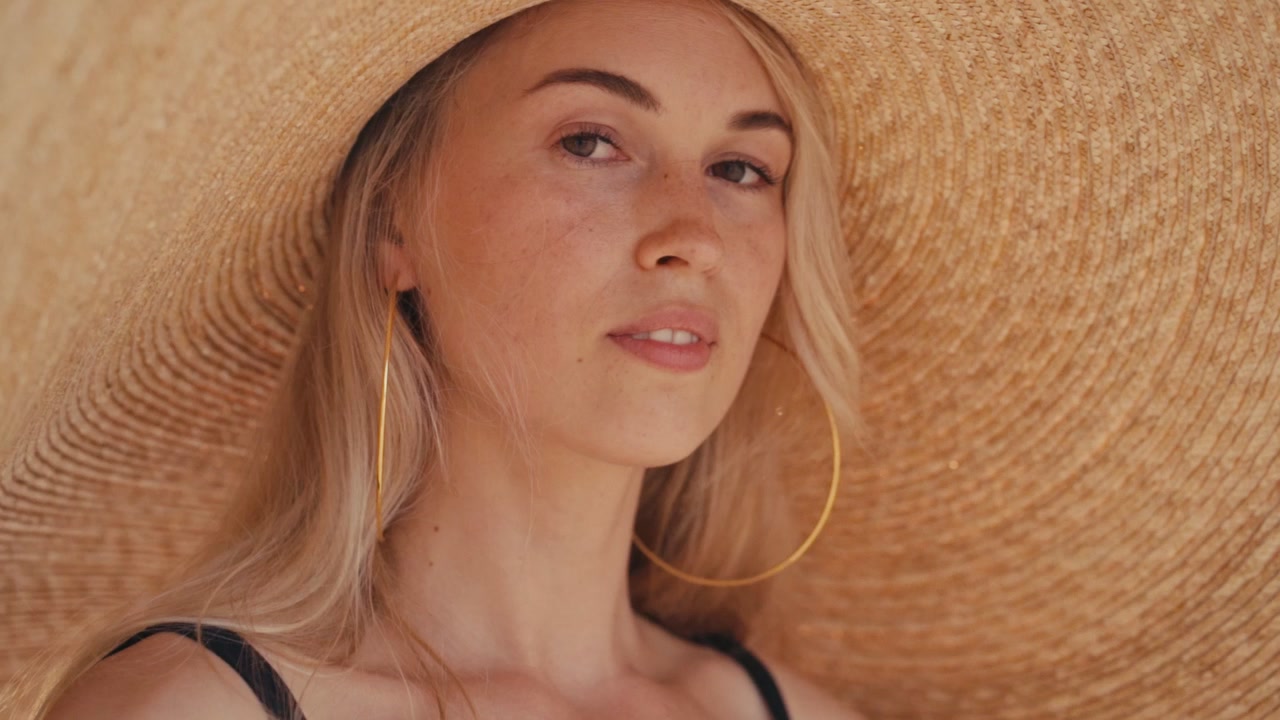 Giovane donna con un grande cappello di paglia in spiaggia