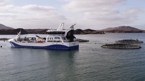 drone shot circumnavigating a a well-boat as it maintains a fish farm