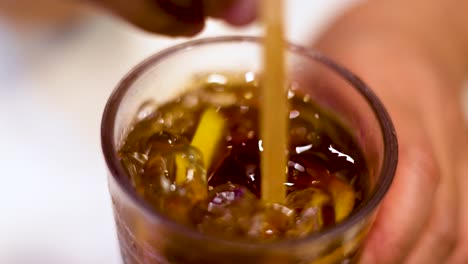 hand stirring iced lemon tea with a straw