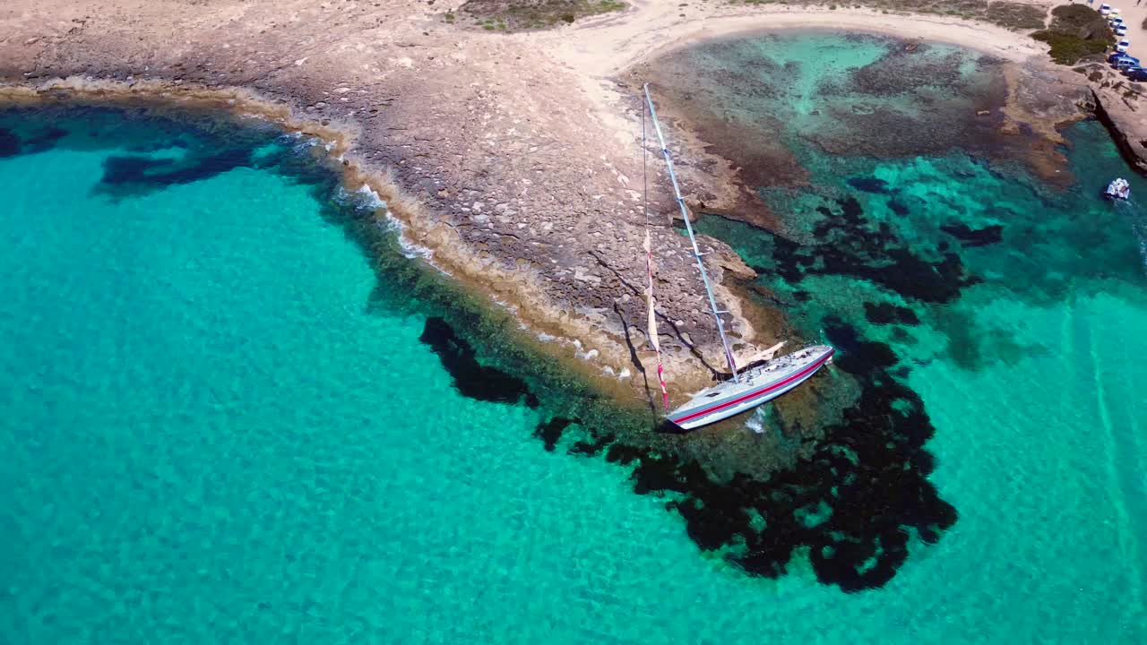Sailboat stranded on cliff near the coast of Formentera Island, Spain, during a summer sunny day. Lovely aerial view flight speed ramp hyper motion time lapse