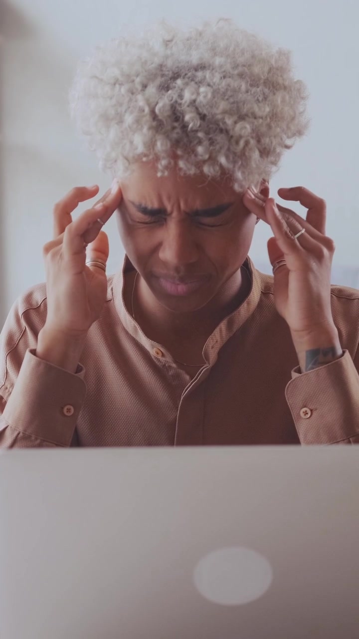 Tired african american woman suffering from headache while using her laptop
