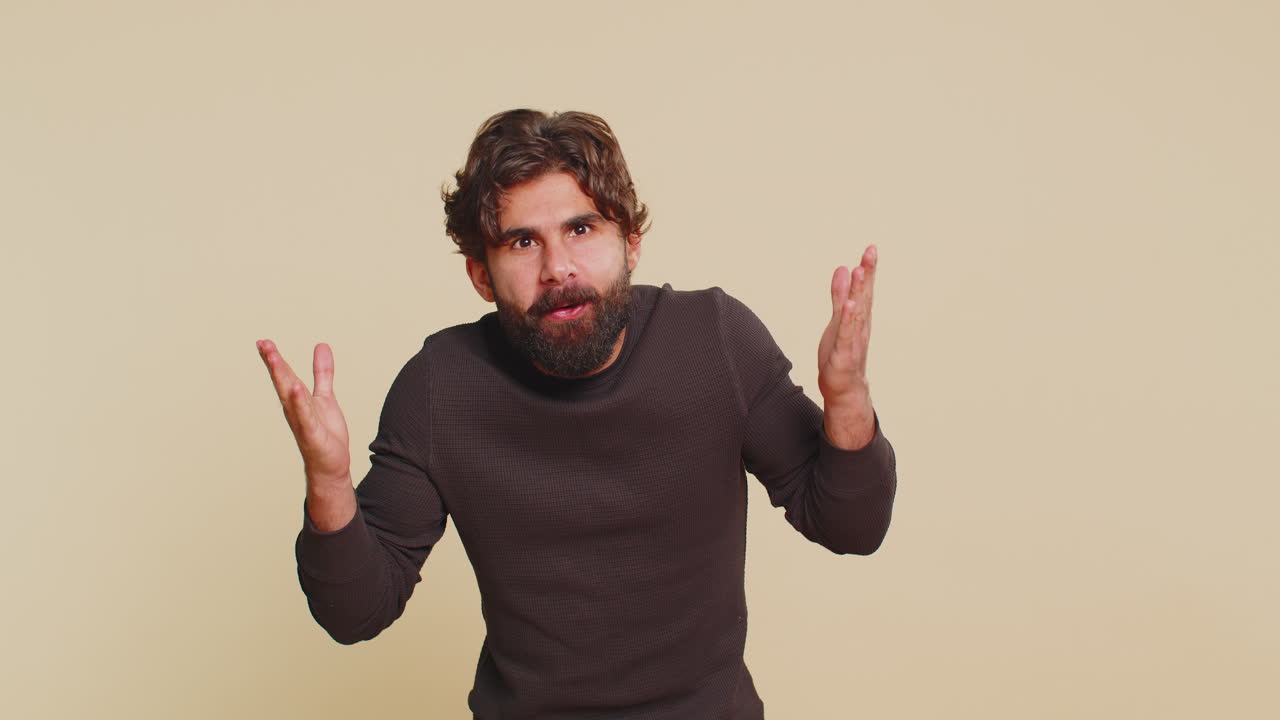 Excited amazed winner hindu man surprise looking at camera with big eyes on beige studio background