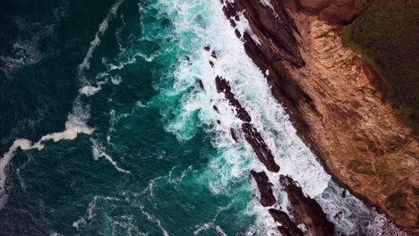 White-Surf-at-Base-of-Tall-Cliff-in-Big-Sur-Cali,-Wide-Overhead-Drone-Shot