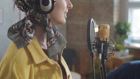 woman in headphones singing in mic during online livestream concert