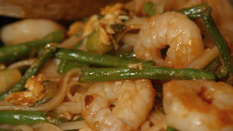 close up of pad thai with king prawns, noodles and beans