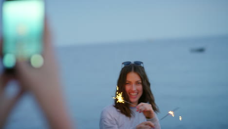 Eine-Glückliche-Frau,-Die-Am-Strand-Mit-Einer-Wunderkerze-Spielt