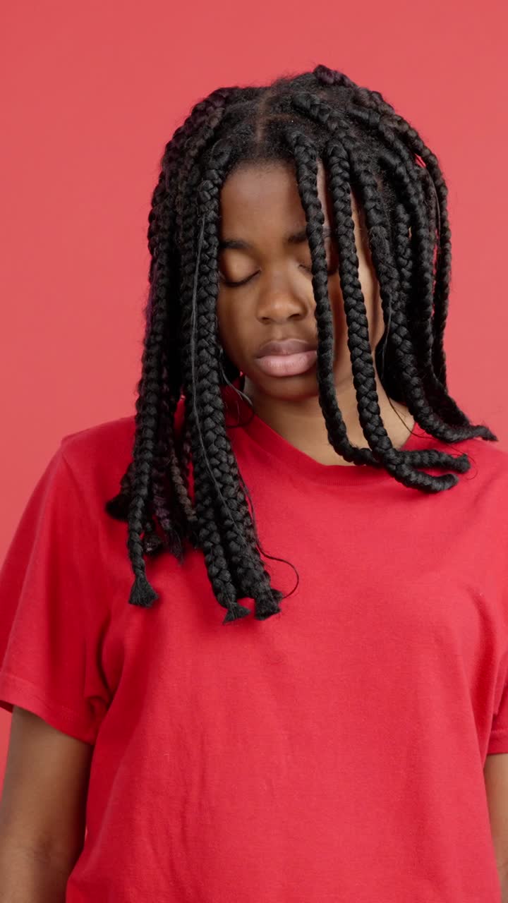 Sad woman with braids against a red background