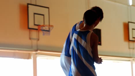 two schoolboys playing basketball in basketball court