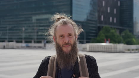 retrato de un hippie barbudo maduro con mochila disfrutando de un viaje urbano en un cálido día soleado en la ciudad en cámara lenta