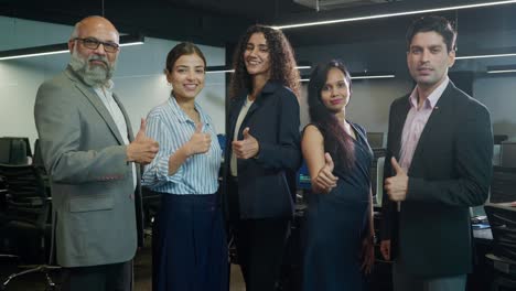 grupo de personas corporativas indias de género mixto con los pulgares hacia arriba mirando a la cámara.