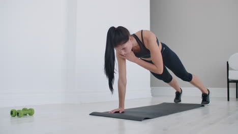 a girl is doing exercises on a mat at home without dumbbells