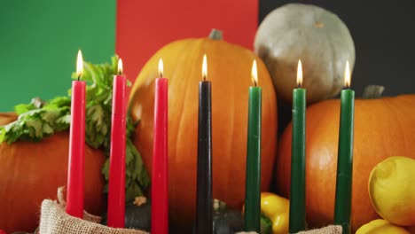 Composition-of-seven-lit-candles-and-halloween-pumpkins-and-vegetables