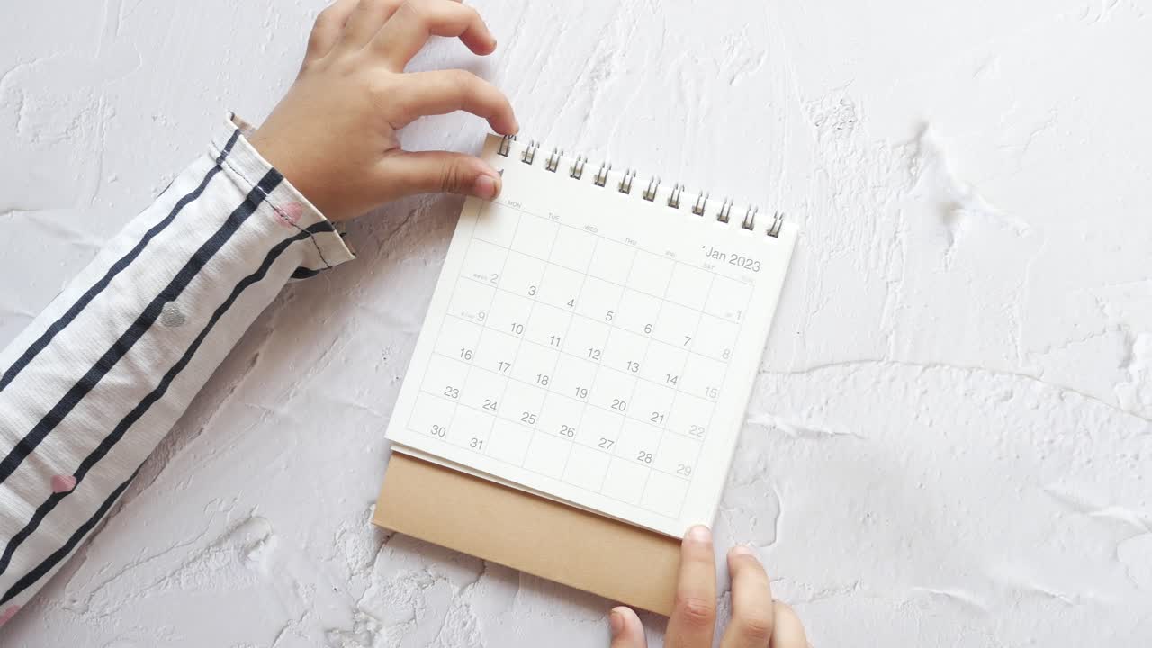 las manos del niño sosteniendo un calendario de enero de 2023