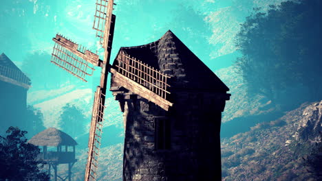 a stone windmill with wooden blades stands in a foggy rural landscape