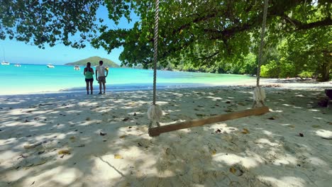 Mahe-Seychelles-port-launay-Couple-watching-the-sea-view,-swing-on-the-beach