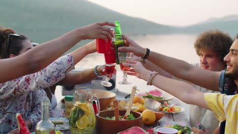 young people toasting with drinks at lake party