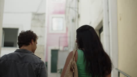 young couple walking along narrow european street.