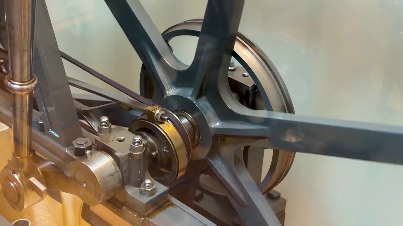 Detailní záběr zblízka modelu mechanického parního stroje s rotujícími železnými ozubenými koly.