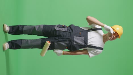 full body of asian man painter wearing safety helmet wiping the sweat and being tired while standing in the green screen background studio
