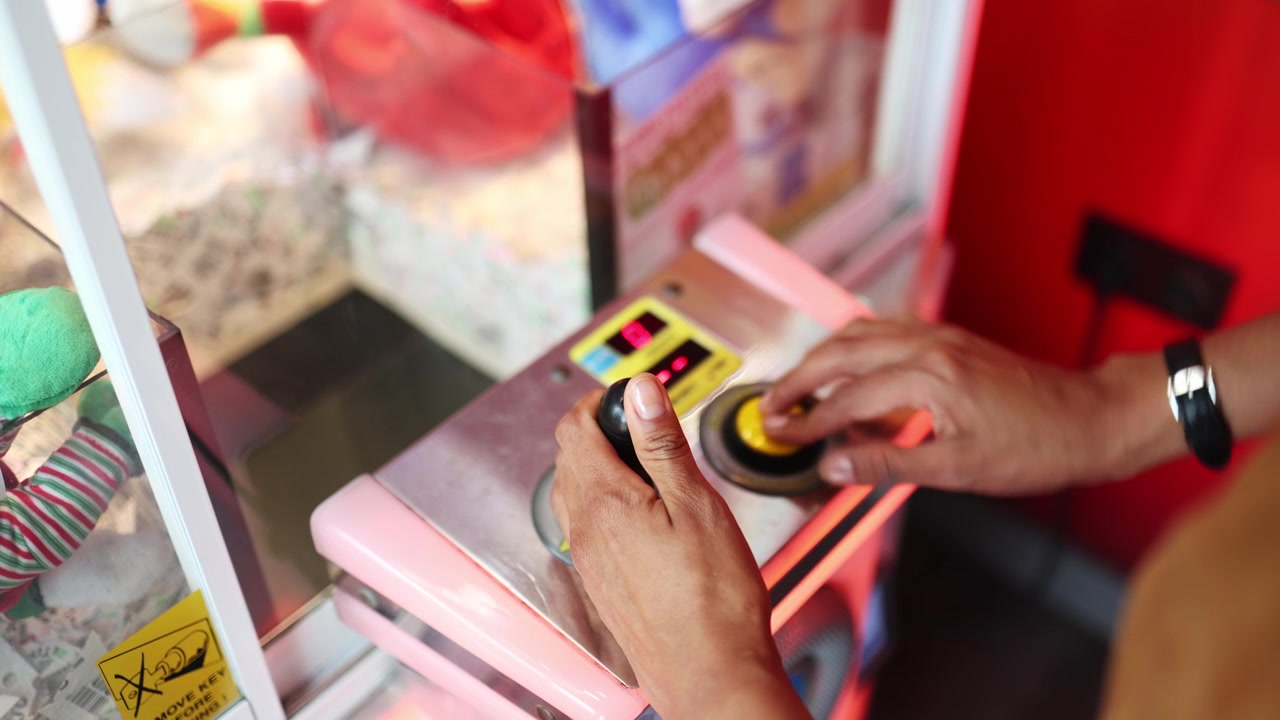 Primo piano di mani che giocano a una macchina artiglio in una sala giochi