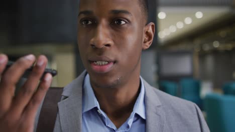 african american businessman talking on smartphone in corridor of modern office