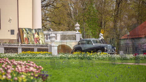 Vintage-car-parked-near-Pakruojis-manor-building-complex,-time-lapse-view